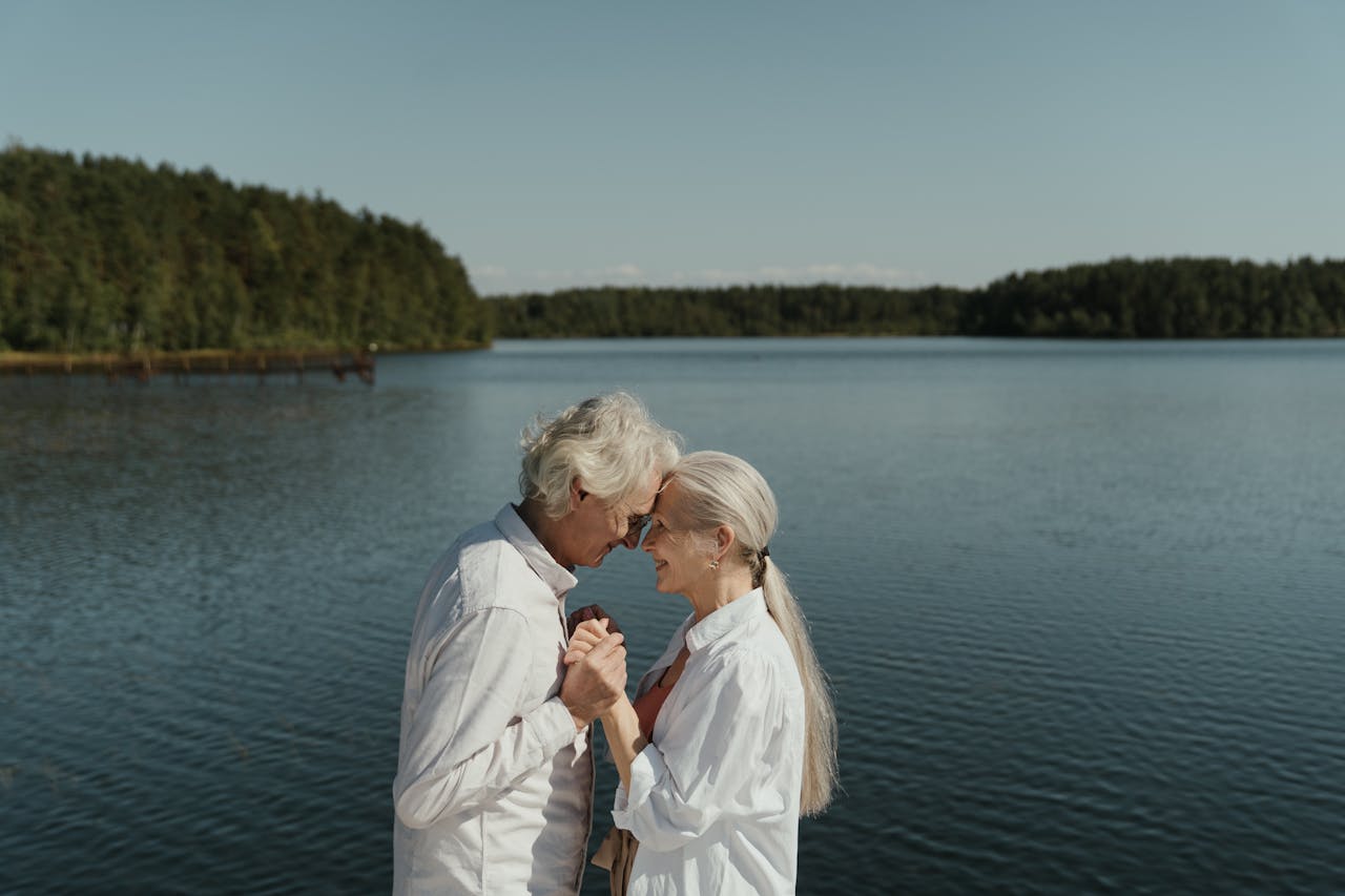 Senior couple in love sharing a tender moment by a tranquil lakeside.